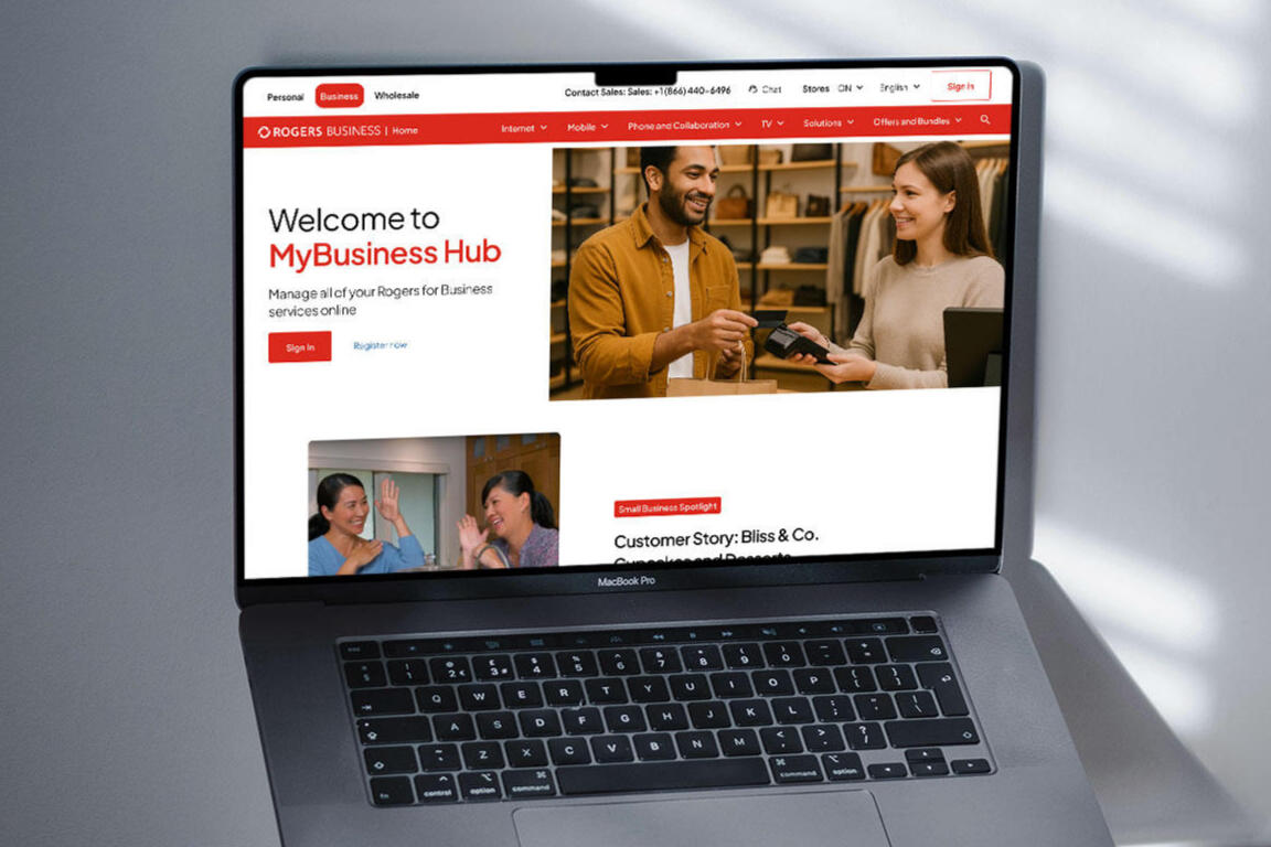 A laptop on a stand showing Rogers Business reimagined landing page in a room with a white wall and wooden desk.